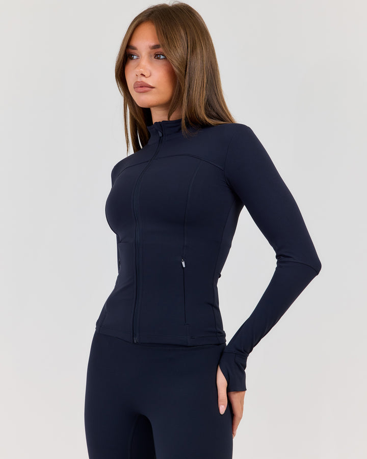 Woman wearing a navy blue athletic outfit on a light gray background