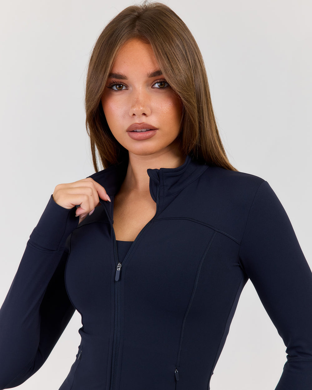 Woman wearing a navy blue long-sleeve top with a zipper on a white background