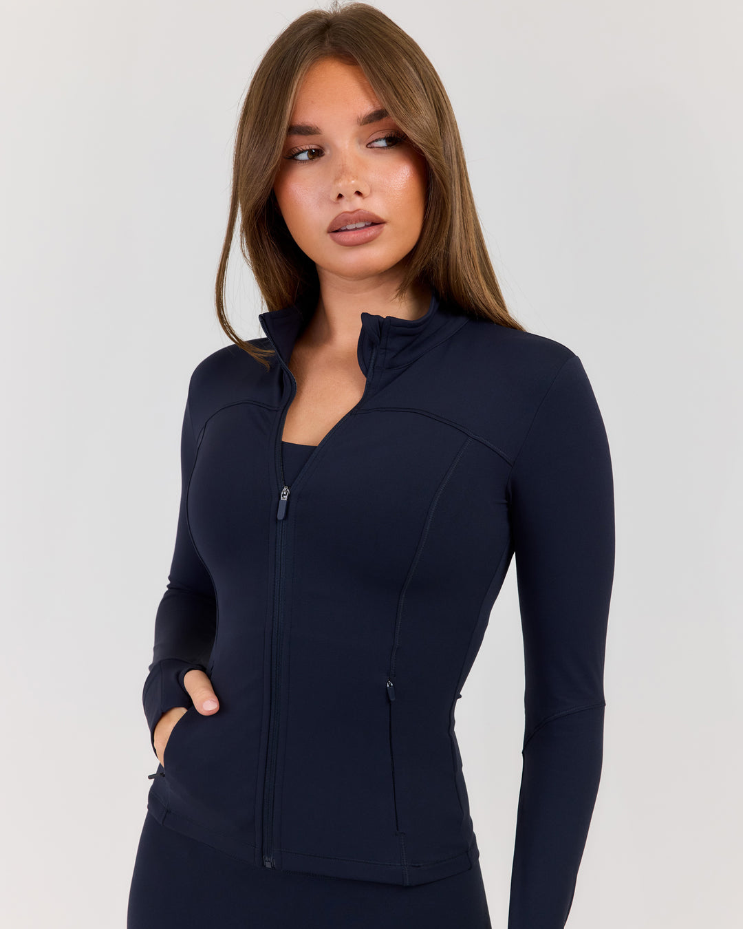 Woman wearing a navy blue jacket on a light gray background