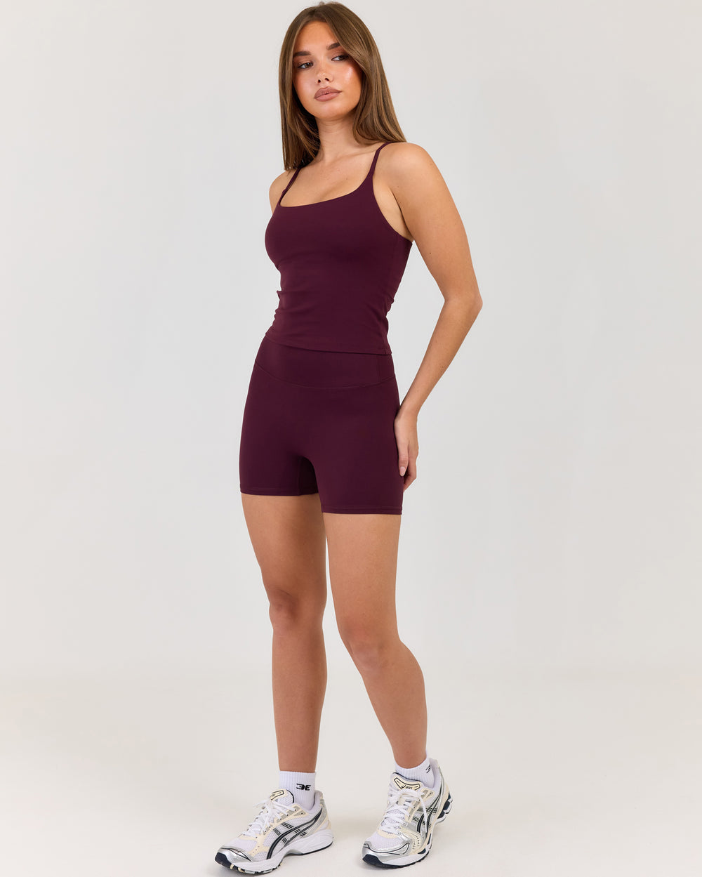 Woman wearing a maroon tank top and shorts set on a white background