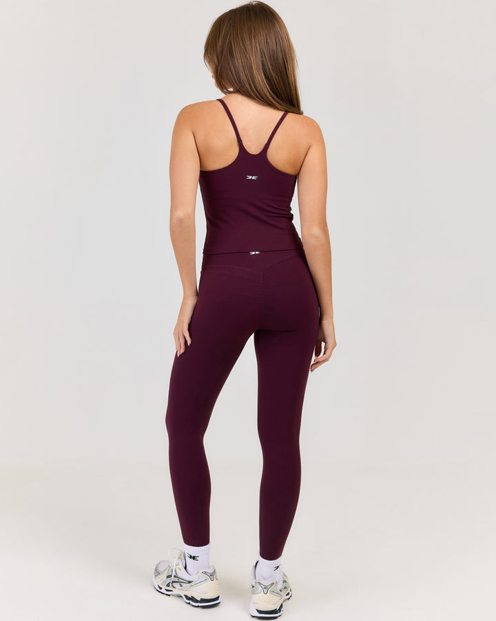 Person wearing a maroon activewear set on a white background