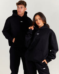 Two people wearing black hoodies with a logo on a light gray background