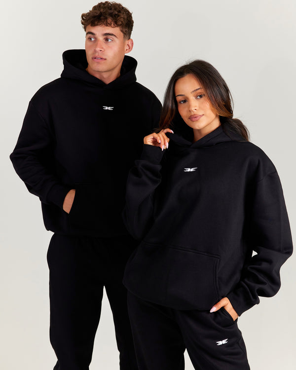 Two people wearing black hoodies with a logo on a light gray background